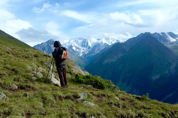 Fototapeta premium Silhouette of a man tourist on a background of a mountain landscape. Among the high snow-capped mountain peaks. Poster or postcard.