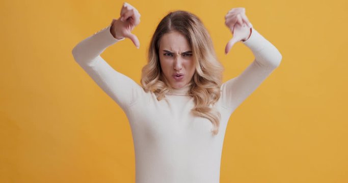 Emotional woman showing thumbs down gesture as rejection