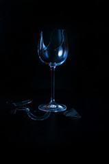 Broken wine glass blue black background closeup copy space
