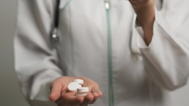 Female doctor holding treatment pills in front of the camera