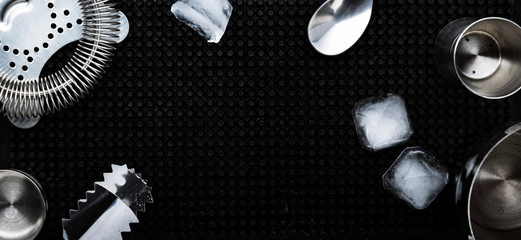 Steel bar tools and accessories for making cocktail. Shaker, jigger, strainer, spoon, tongs, muddler. Alcohol drink and beverages preparation concept. Black background, top view, copy space