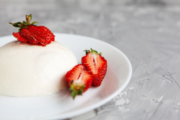 italian dessert panna cotta with fresh strawberries and a banana on a grey concrete background