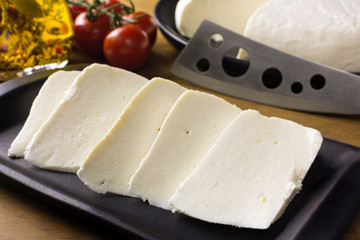 Slices of buffalo fresh cheese made in Serra da Canastra, in a platter in wood background