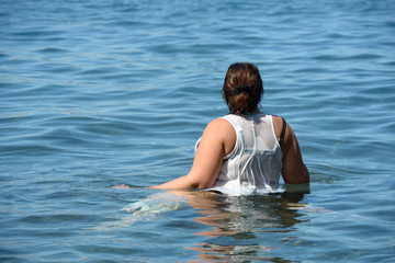 Rear view of woman that is standing in calm water.