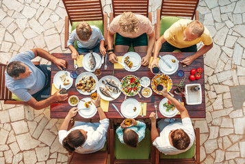 Big multigenerational family dinner in process.  Table with food and hands. Food consumption and multigenerational family Top view image concept image.