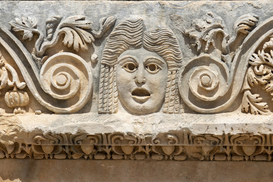 Fragment of the facade with the image of stone masks of the Greco-Roman amphitheater of the ancient city of Myra in Demre