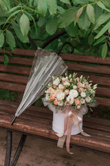 A large flower arrangement in a big white hat box in rainy day was created by a florist for a wedding gift. white freesia,  ranunculus asiaticus, eustoma flowers, roses and eucalyptus in flowers box