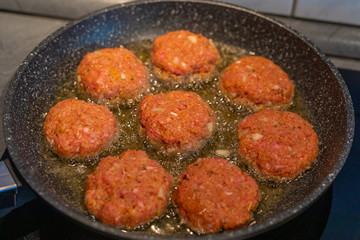 Raw meat cutlets rissole meatballs of minced pork in a pan.