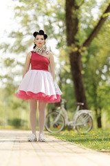 Retro style photo. A girl in a pink dress and hairstyle in the style of the 40-50s dances and poses...