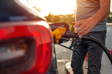 Cropped shot of a handsome young man refuelling his car at a gas station. Portrait of a Young Man...