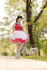 Retro style photo. A girl in a pink dress and hairstyle in the style of the 40-50s dances and poses...
