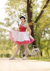Retro style photo. A girl in a pink dress and hairstyle in the style of the 40-50s dances and poses...