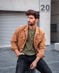 Handsome modern man sitting on the street in city, Male fashion model dressed casually. - 349015433