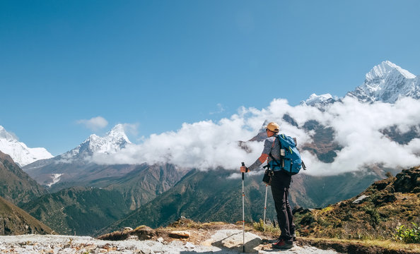 Young hiker backpacker man with trekking poles enjoying the Ama Dablam 6814m peak mountain during high altitude acclimatization walk. Everest Base Camp route, Nepal. Active vacations concept image