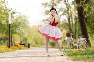 Retro style photo. A girl in a pink dress and hairstyle in the style of the 40-50s dances and poses...