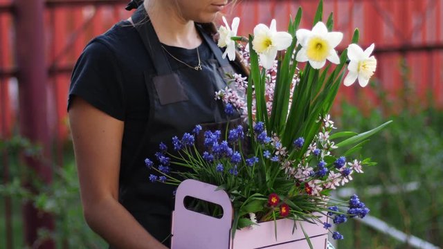 Gardener girl with a box of flowers. Congratulations to Mother's Day