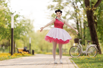 Retro style photo. A girl in a pink dress and hairstyle in the style of the 40-50s dances and poses...