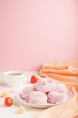 Pink strawberry homemade zephyr or marshmallow with cup of coffee on white and pink background. side view, selective focus, copy space.