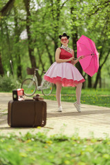 Retro style photo. A girl in a pink dress and hairstyle in the style of the 40-50s holds a pink...