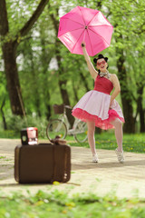 Retro style photo. A girl in a pink dress and hairstyle in the style of the 40-50s holds a pink...