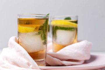 tea with ice, mint and lemon wedges on white table