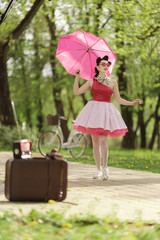 Retro style photo. A girl in a pink dress and hairstyle in the style of the 40-50s holds a pink...