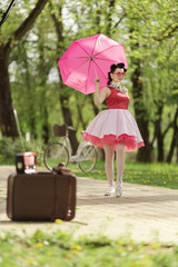 Retro style photo. A girl in a pink dress and hairstyle in the style of the 40-50s holds a pink...