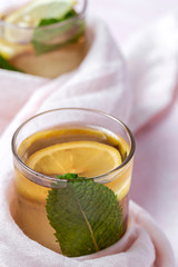 tea with ice, mint and lemon wedges on white table