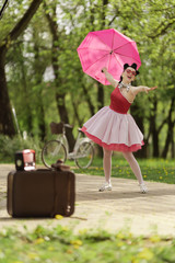 Retro style photo. A girl in a pink dress and hairstyle in the style of the 40-50s holds a pink...
