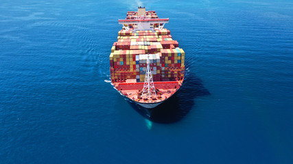Aerial drone photo of huge container cargo Ship carrying load in truck-size colourful containers...