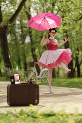 Retro style photo. A girl in a pink dress and hairstyle in the style of the 40-50s holds a pink...