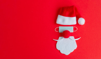 Santa Claus hat and beard with face mask on a red background, creative minimal concept of Christmas and New Year