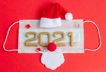 New year numbers 2021, Santa Claus hat and beard on face mask on a red background, creative minimal concept of Christmas