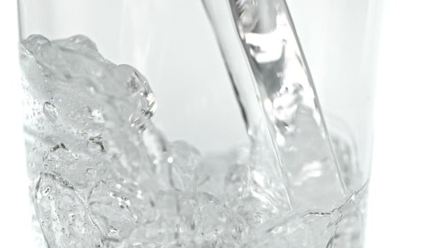 Super Slow Motion Detail Shot of Pouring Fresh Water into Glass at 1000fps, Isolated on White Background.