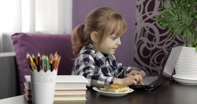 Girl doing online homework using digital laptop computer. Distance education
