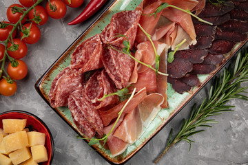 
Jamon, parma, herbs, Parmesan on a plate as a snack