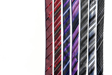 Pattern formed by a row of different colour ties. Plain white background. Copy space