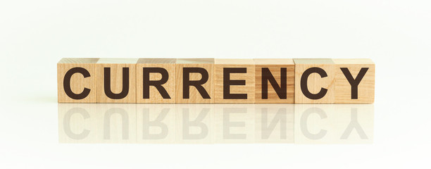 CURRENCY - word from wooden blocks with letters, front view on white background