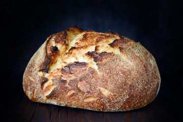 Homemade Freshly Baked Country Bread  made from wheat and whole grain flour on a dark background. French Freshly baked bread. Slicing homemade bread 