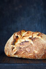 Homemade Freshly Baked Country Bread  made from wheat and whole grain flour on a dark background. French Freshly baked bread. Slicing homemade bread 