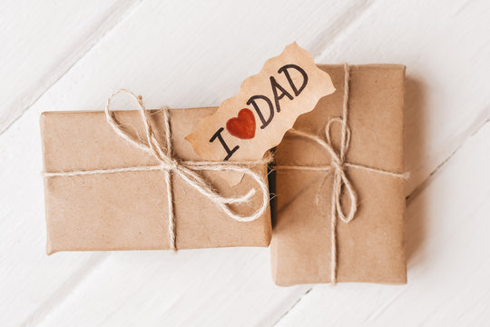 Gift box with a tag on white wooden background. Father's day or birthday concept.