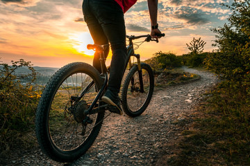 Mountain biker on trail. Back shot of mountain biker at sunset on a modern off-road bike on the hill behind the city.