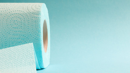 Blue roll of modern toilet paper on a blue background. A paper product on a cardboard sleeve, used for sanitary purposes from cellulose with cutouts for easy tearing. Embossed drawing. copy space.