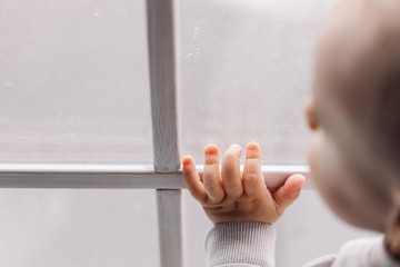 Child holding window glass standing near rainy window with space for design