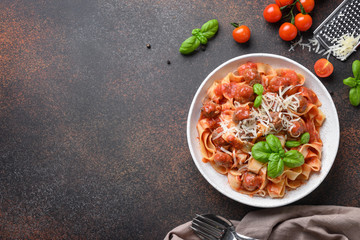 Italian pasta fettuccine with meatballs, cheese, tomatoes, basil. Top view. Space for text.