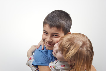 Portrait of adorable happy sister and brother hugs on a white background