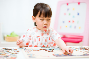toddler girl playing wooden puzzle at home