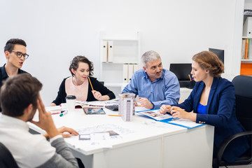 Obraz premium Colleagues having a meeting in a conference room. A group of people having a conversation while showing their designs for approval