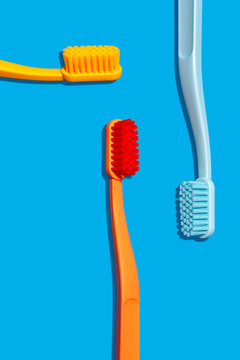 Modern Monochromatic Yellow, Orange and Blue Toothbrushes Layout on Blue Background