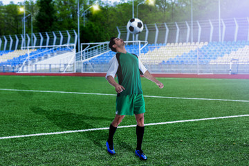 Young man in uniform playing football at stadium